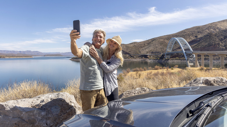Couple standing in front of a lake taking a selfie