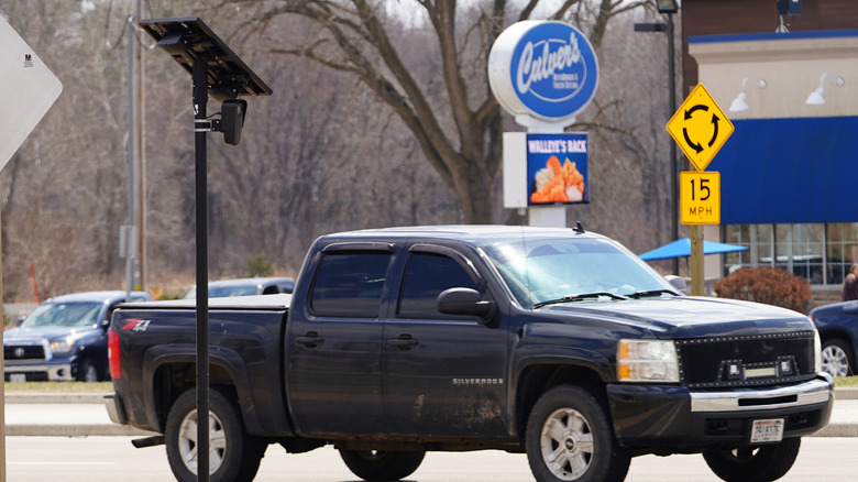 A pickup truck drives by a Flock license plate reader