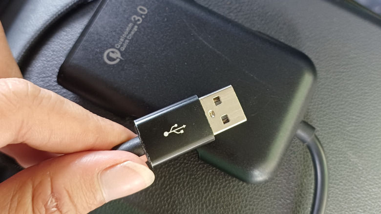 Person holding a USB cable with the trident logo displayed