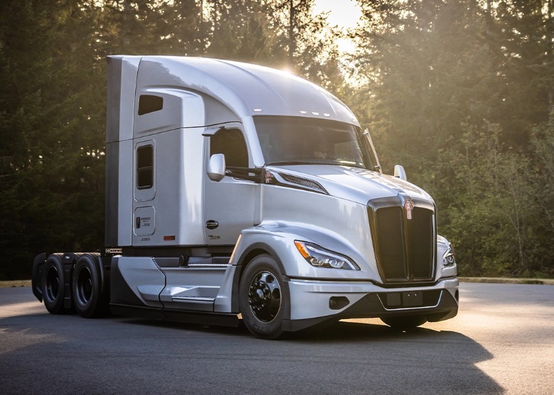 A front 3/4 shot of a silver Kenworth T680 semi-truck parked with no trailer.