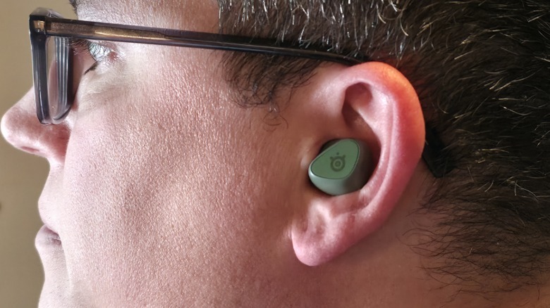 A man wearing an Arctis GameBud in his left ear