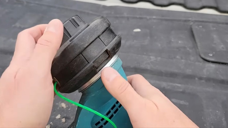 A close-up showing the push button release for the spool on a Makita string trimmer