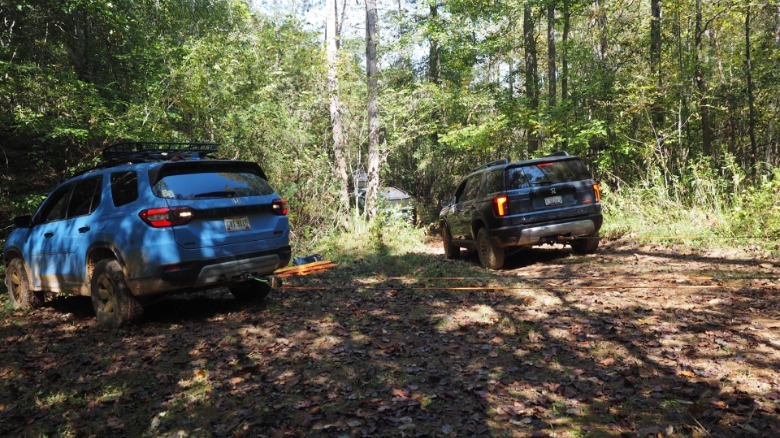 2027 Honda Passport TrailSport pulls a Honda Pilot out of a ditch with the use of off-road recovery tools and a nearby tree