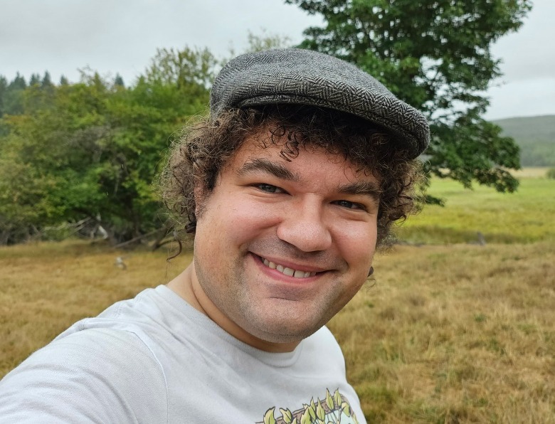 man standing in grass by trees