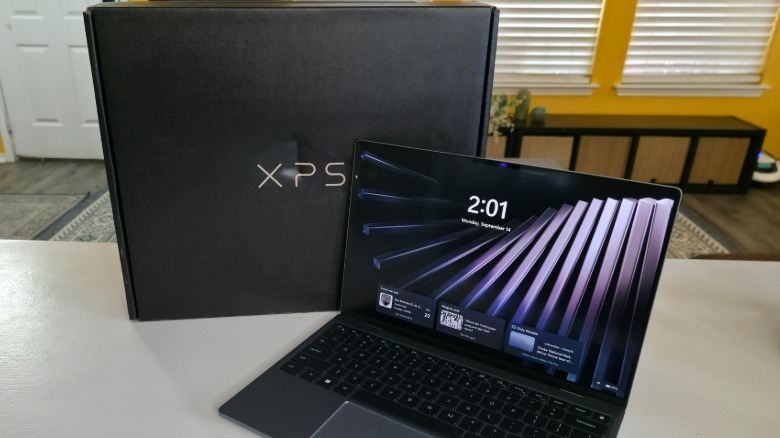The Dell XPS 13 open with its lock screen in front of the computer's box
