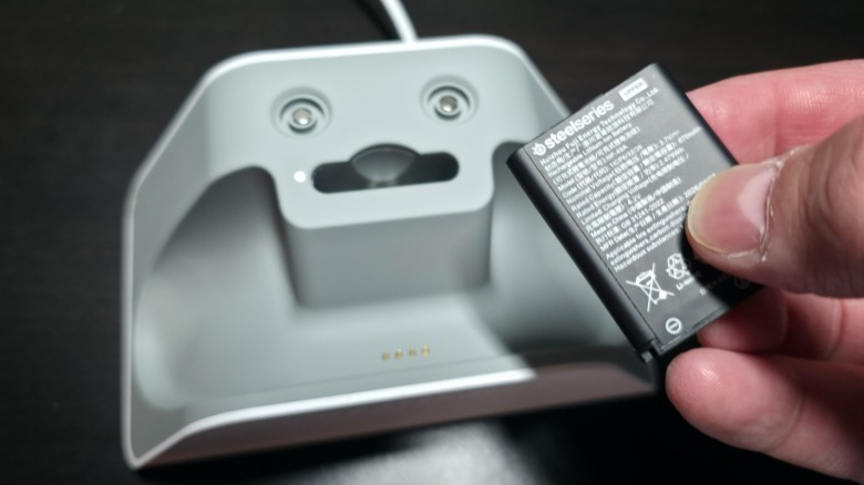 A hand holding a spare battery for the SteelSeries Aeon Pro Controller