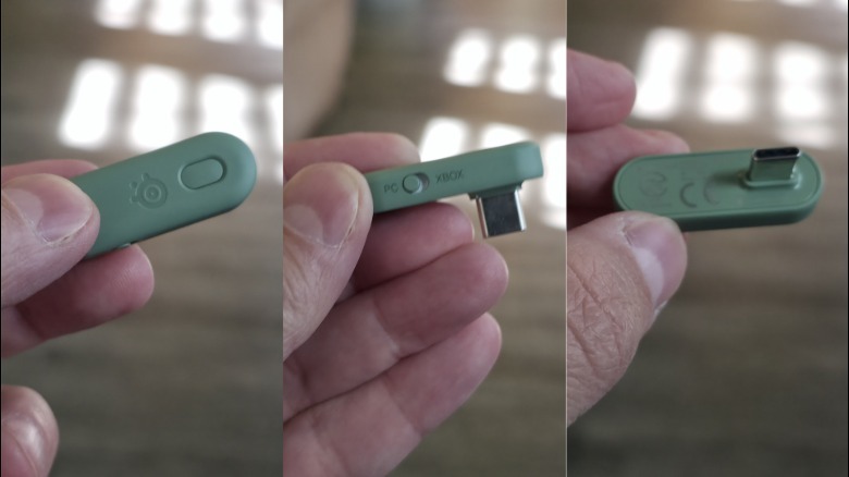 A person holding a small dongle for the Arctis GameBuds