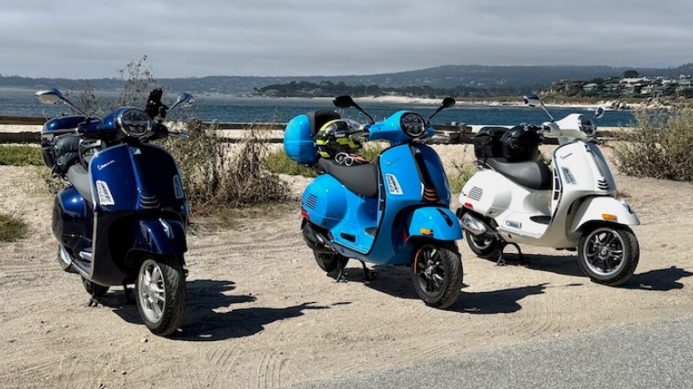 Three Vespas parked on the sand near the ocean
