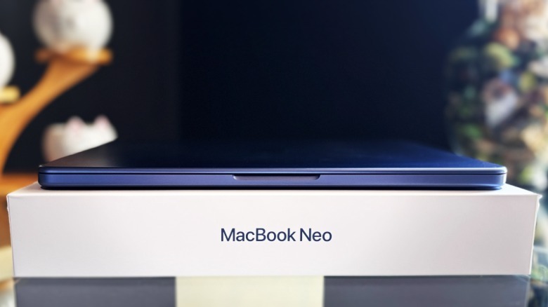 MacBook Neo dengan penutup tertutup berada di atas kotak produknya