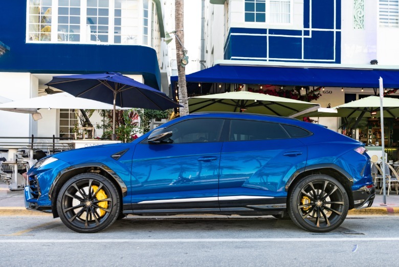 Blue Lamborghini Urus with yellow brake calipers parked along a street