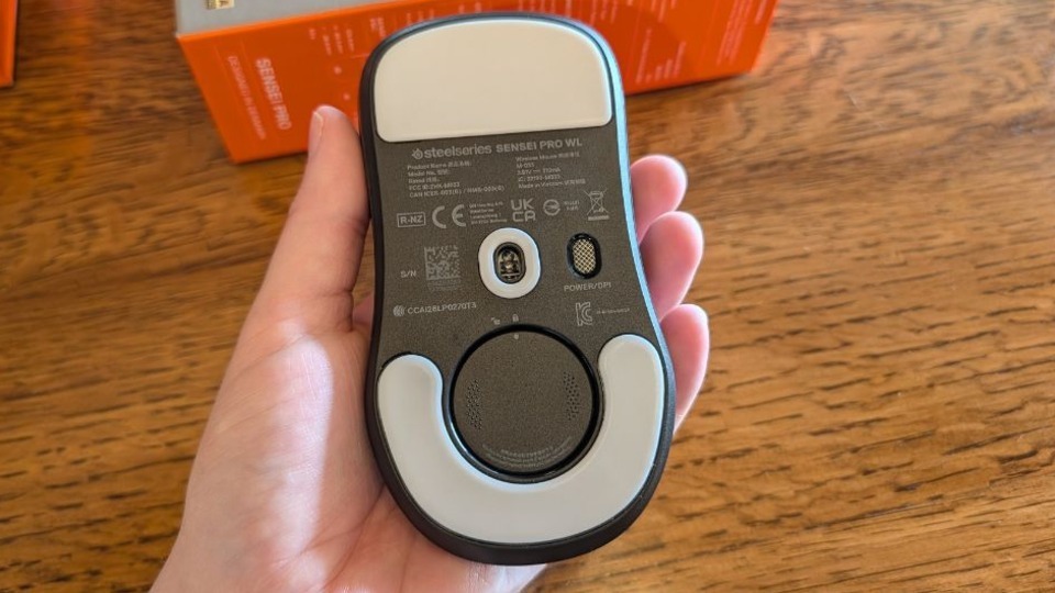 Hand holding the SteelSeries Sensei Pro mouse upside down to show battery