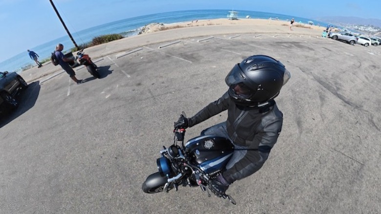 A rider in a beach parking lot using an Insta360 X6 to film
