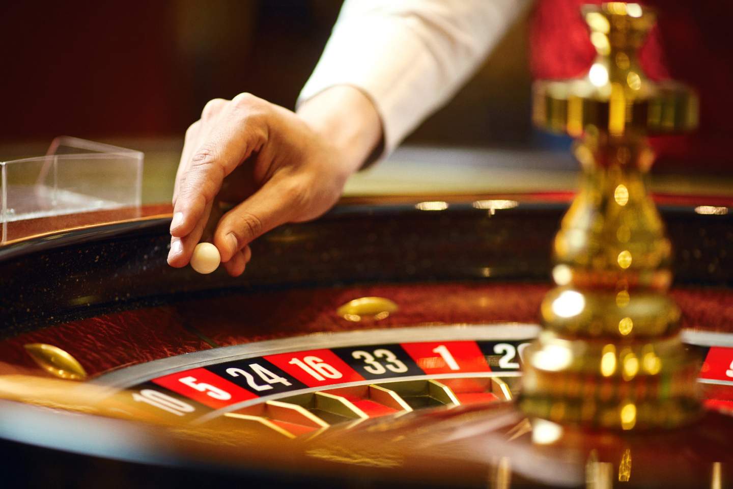 Hand holds a ball over a roulette wheel